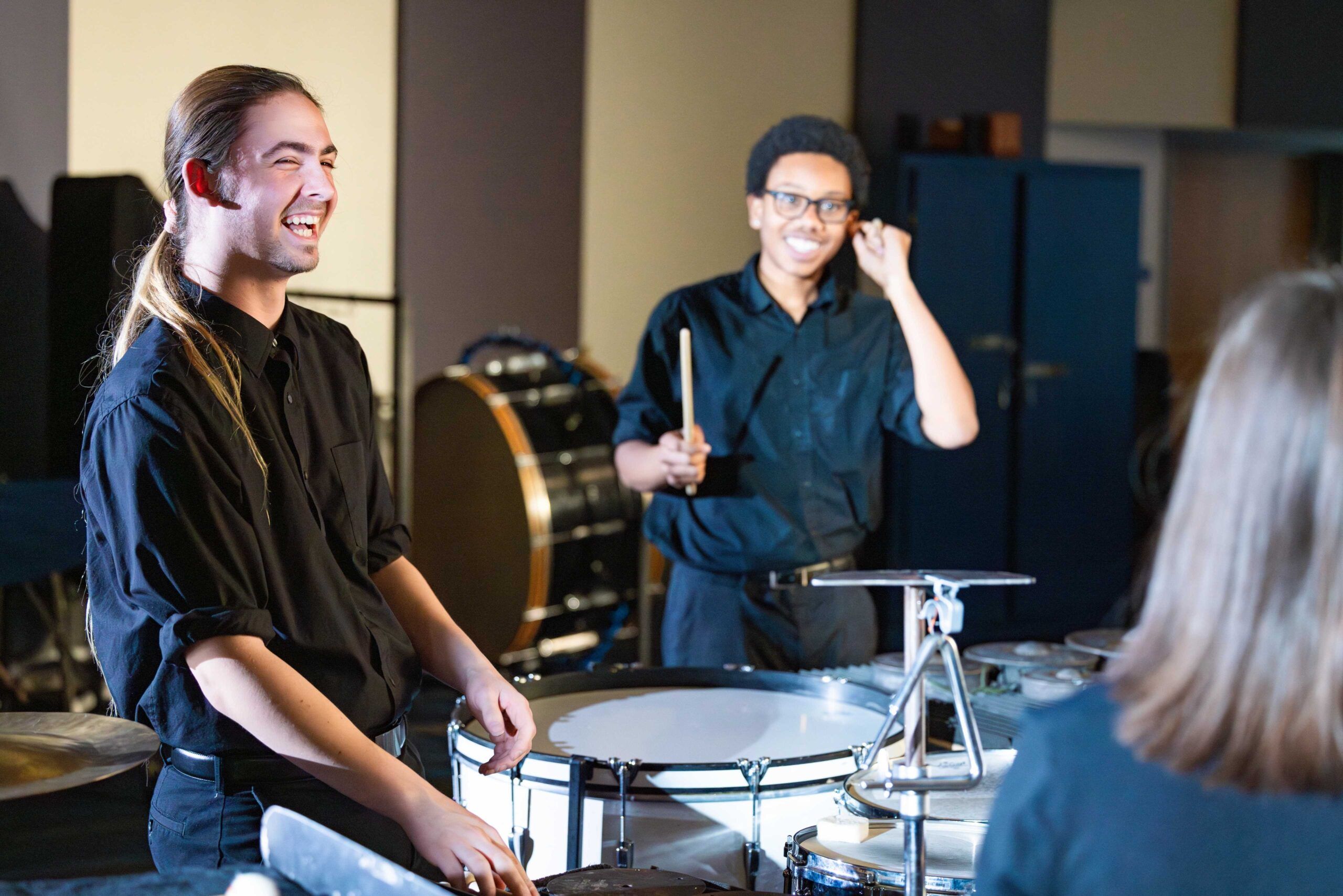 NAU students in the percussion section laugh as they have a jam session in rehearsal.