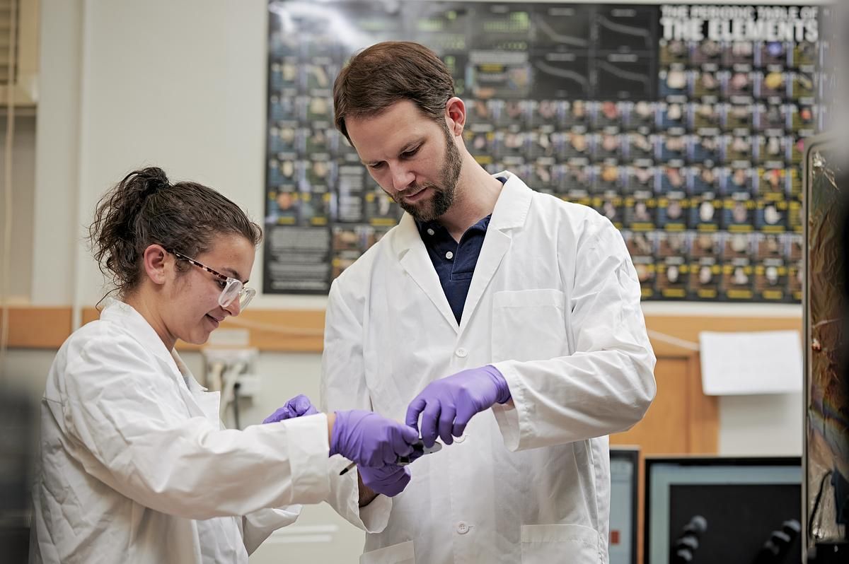 N A U physics students wearing lab coats work in a lab.