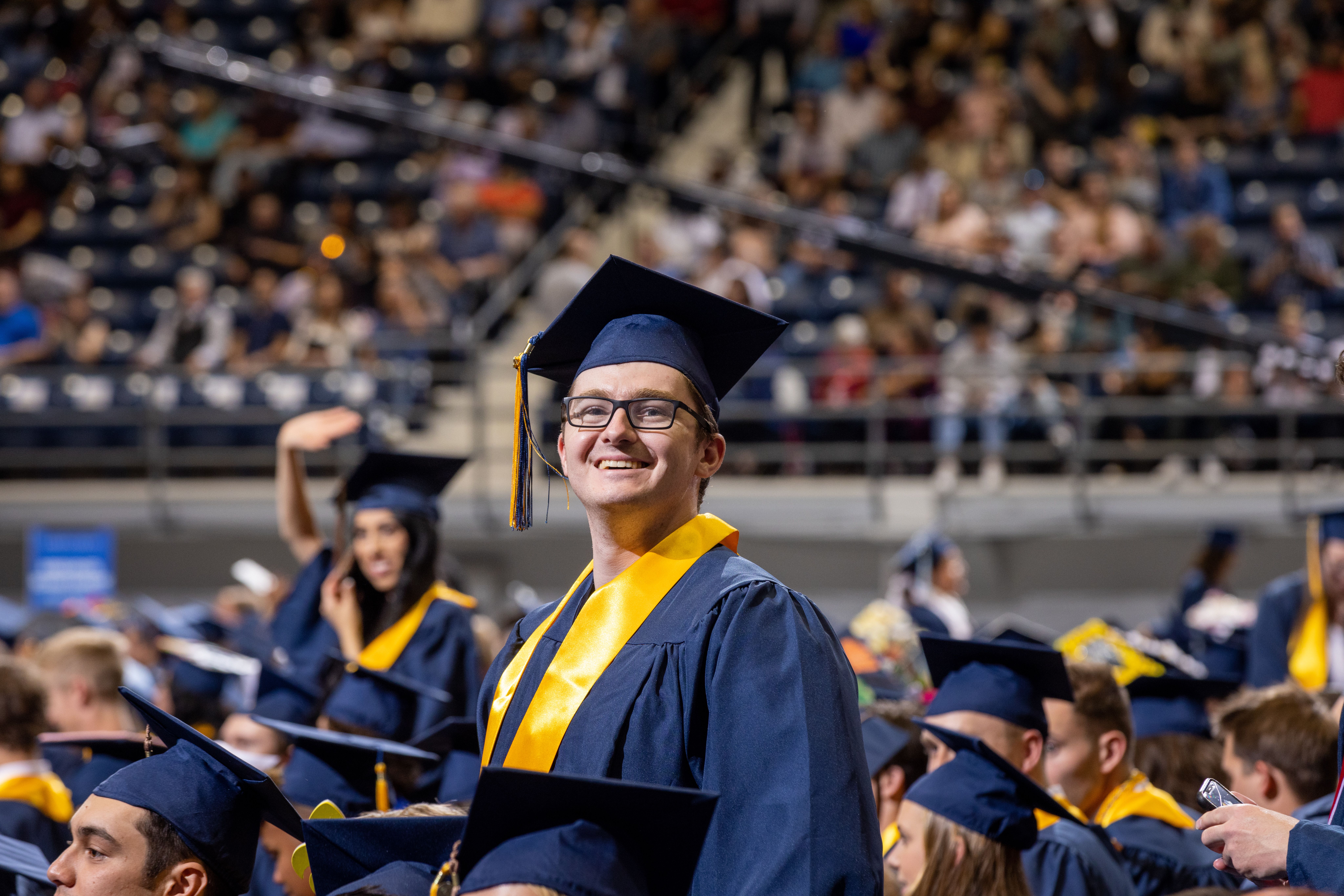 A smiling NAU student standing at commencement.