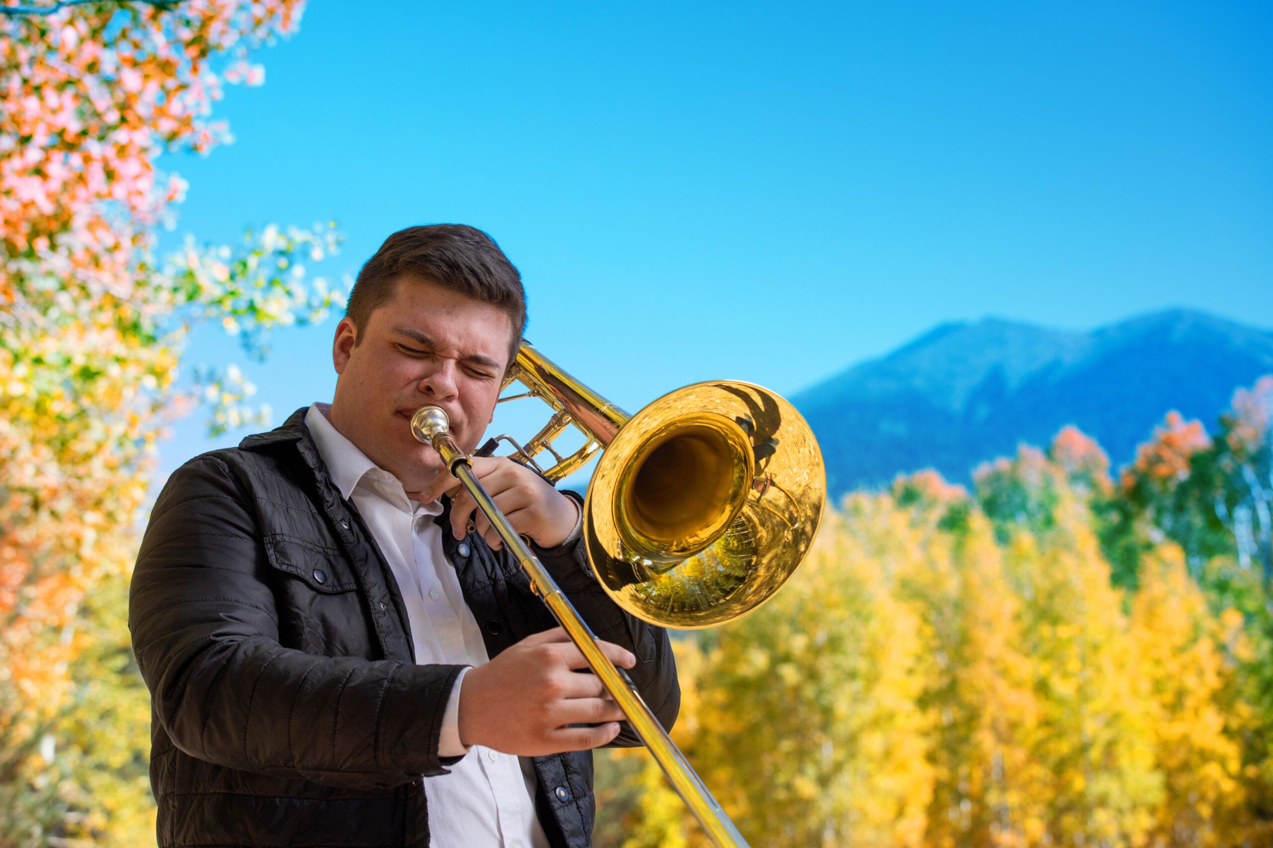 NAU student plays the trombone surrounded by aspen trees in Flagstaff, Arizona.