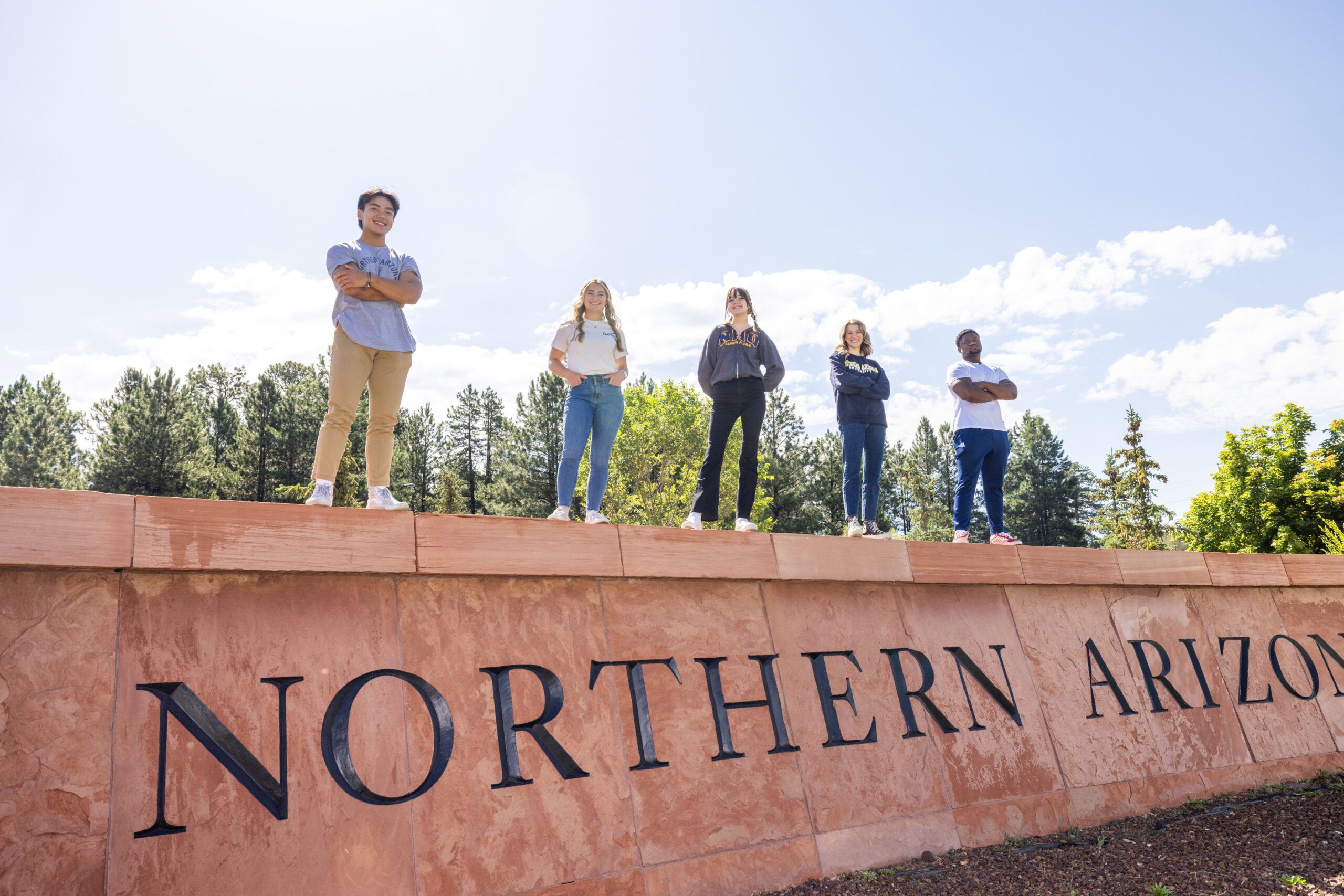 Students standing on a wall that says "Northern Arizona University".