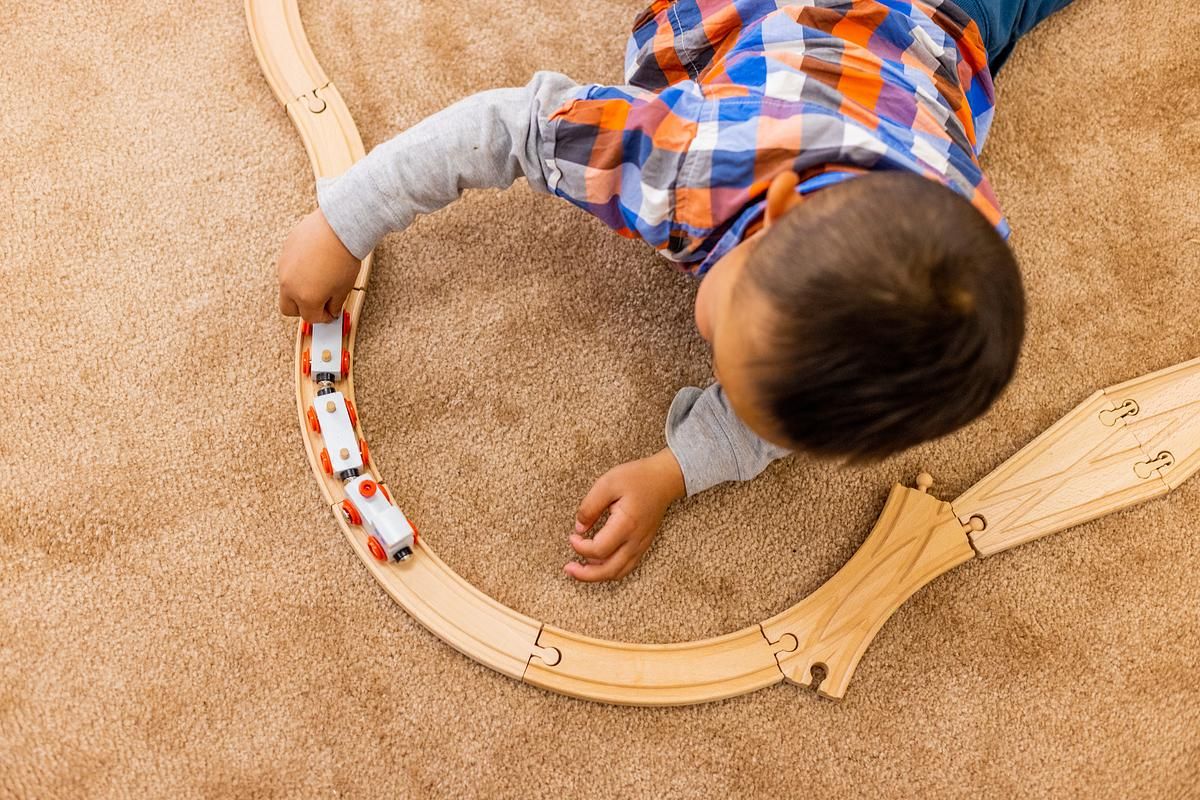 A young child playing with a wooden magnetic train set.